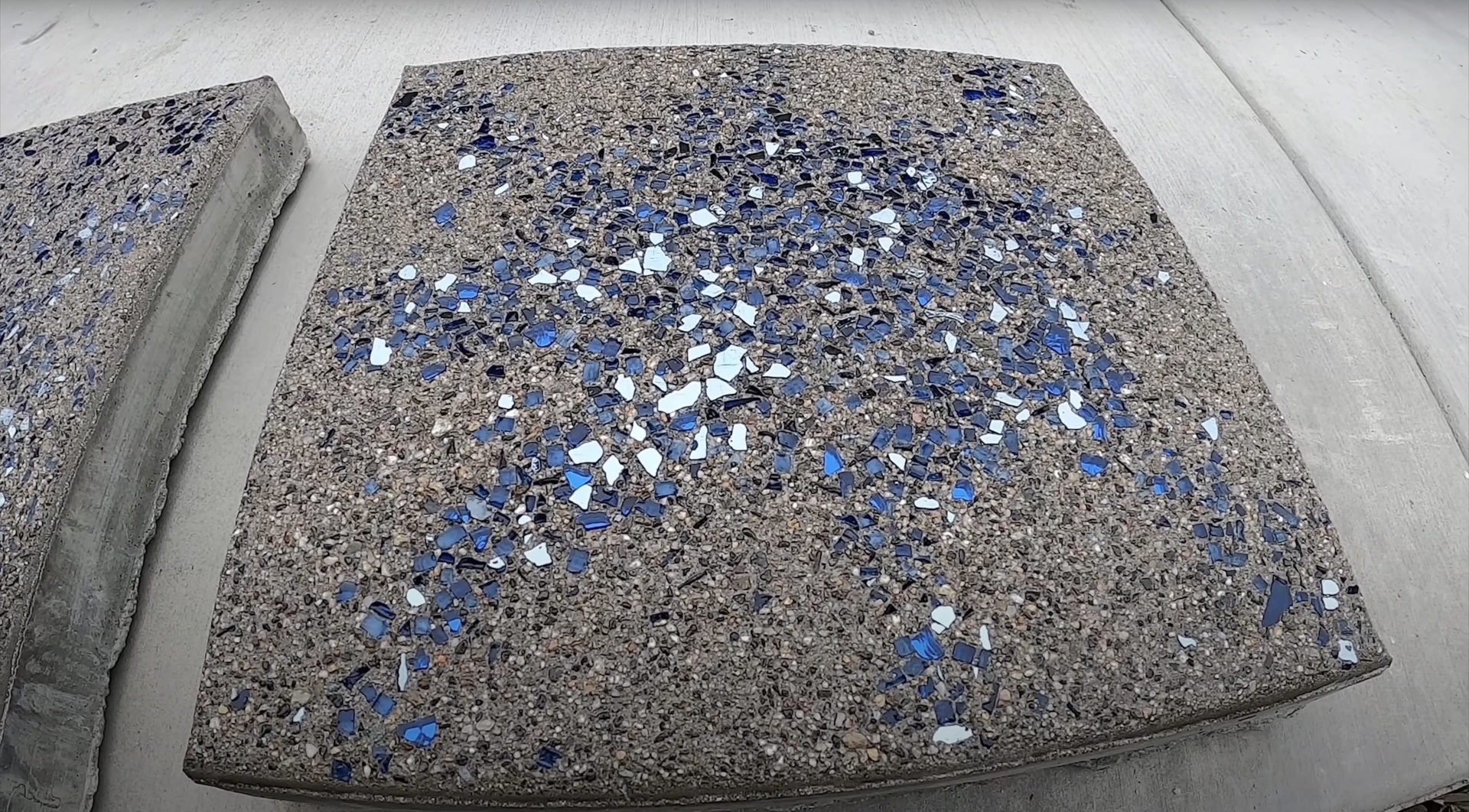Decorative Concrete Options - Exposed aggregate with colored glass accents and design elements Decorative exposed aggregate concrete sample with blue and white glass accents showcasing design options