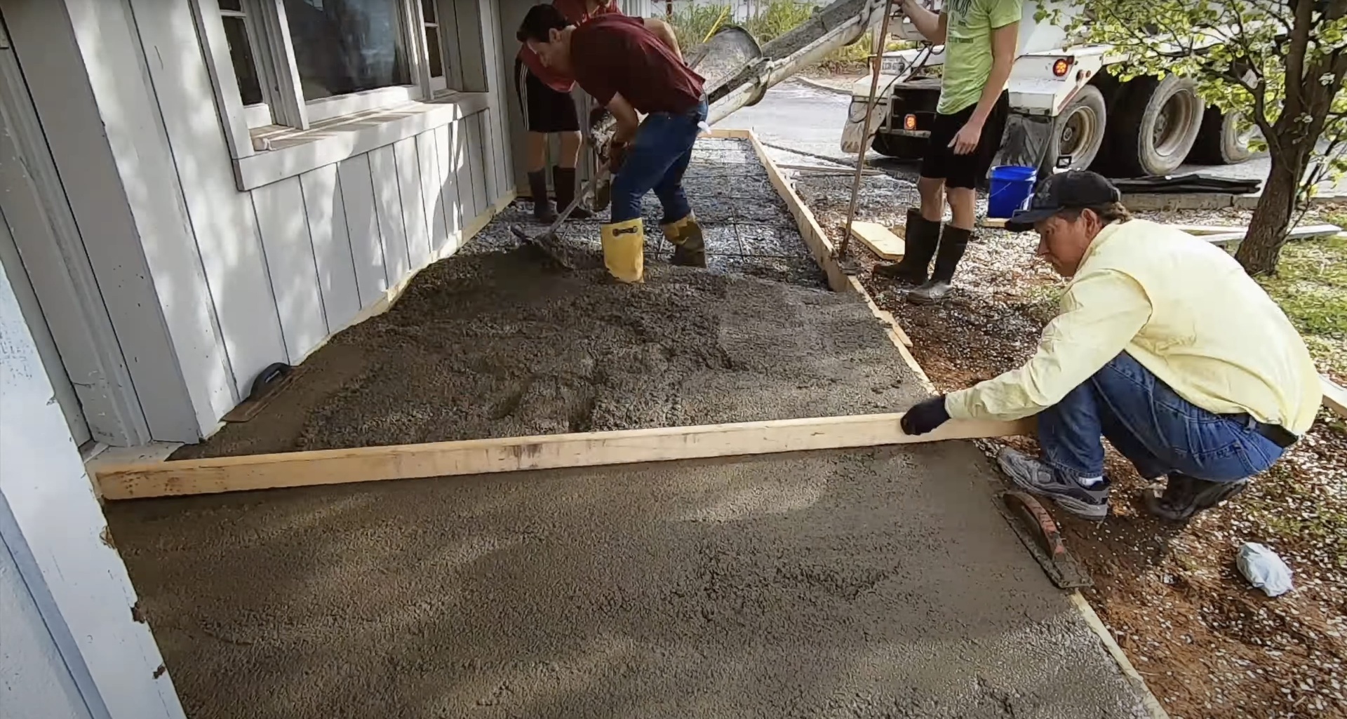 Expert Concrete Slab Installation - Professional team smoothing fresh concrete for perfect finish Professional concrete team smoothing and leveling fresh concrete slab installation for residential driveway project
